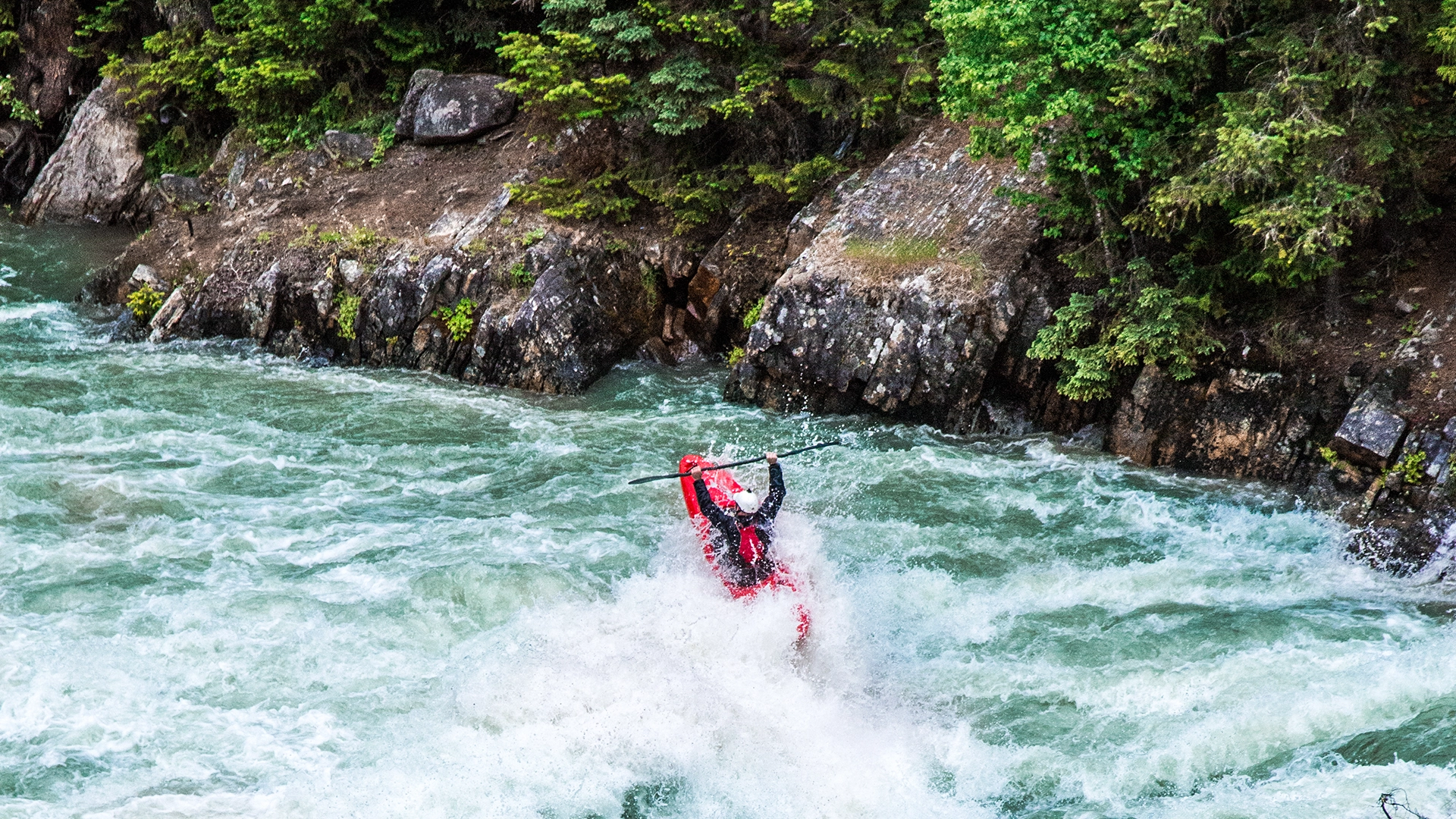 A person kayaking in a fast flowing river